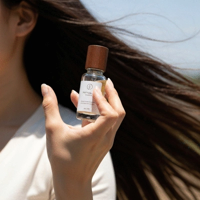 Close-up of a person's hand holding a bottle of natural hair growth serum
