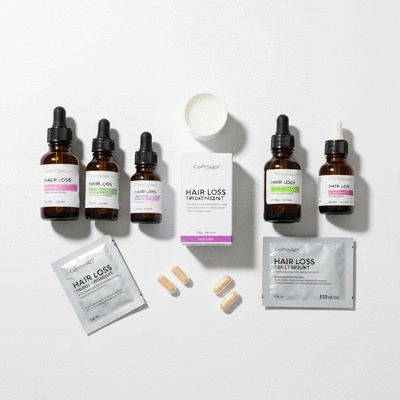 Assortment of hair loss treatment products including bottles, droppers, and supplements arranged neatly on a clean white surface, no text, no words, no typography, clean image